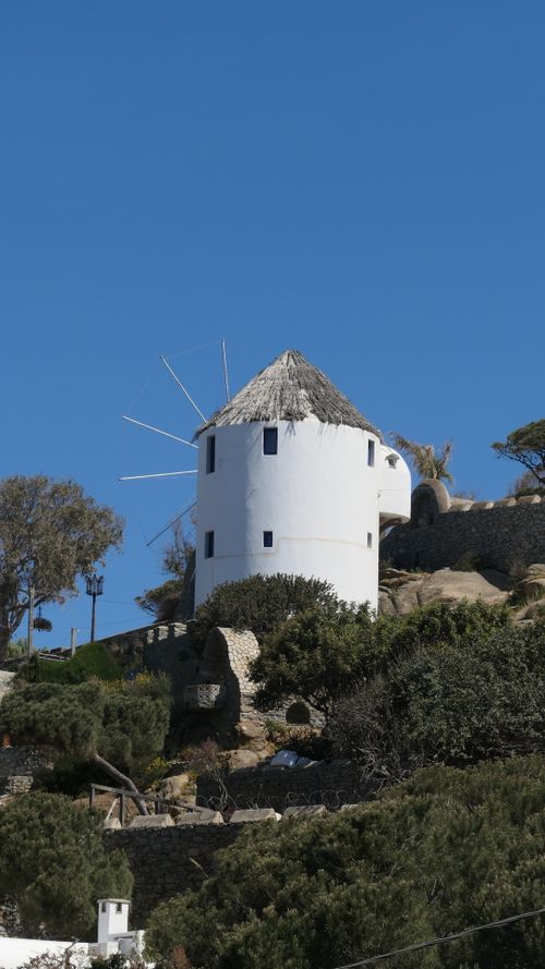 Free A traditional white windmill on a sunny day in Mykonos, Greece, set against a clear blue sky. Stock Photo