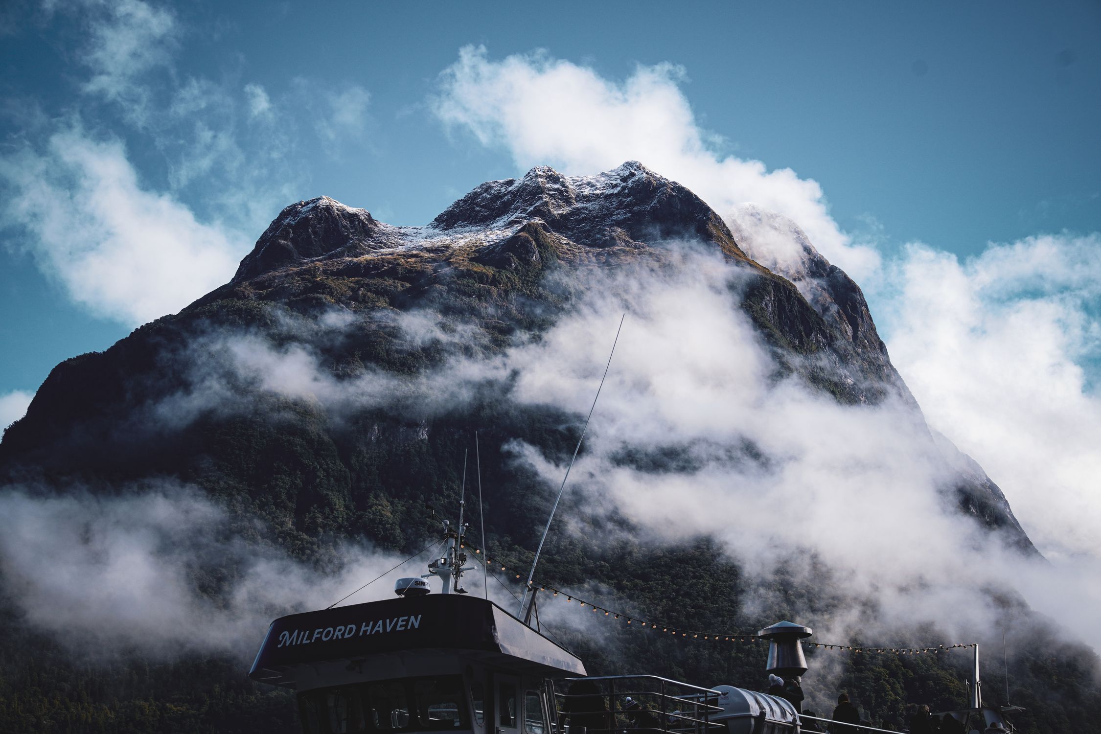 Stunning view of a mist-covered mountain with a boat in the foreground.
