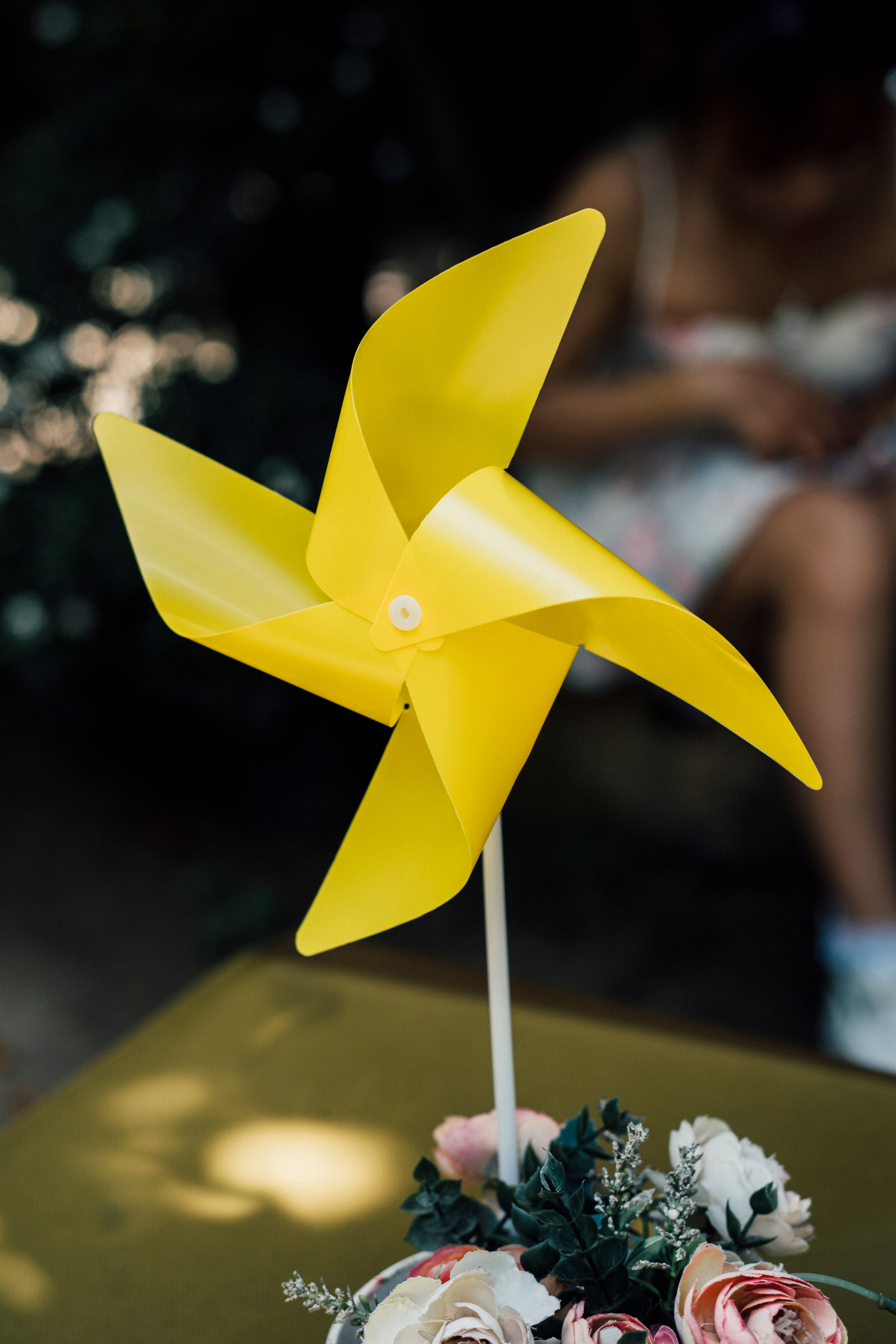 A yellow pinwheel on a table with flowers · Free Stock Photo