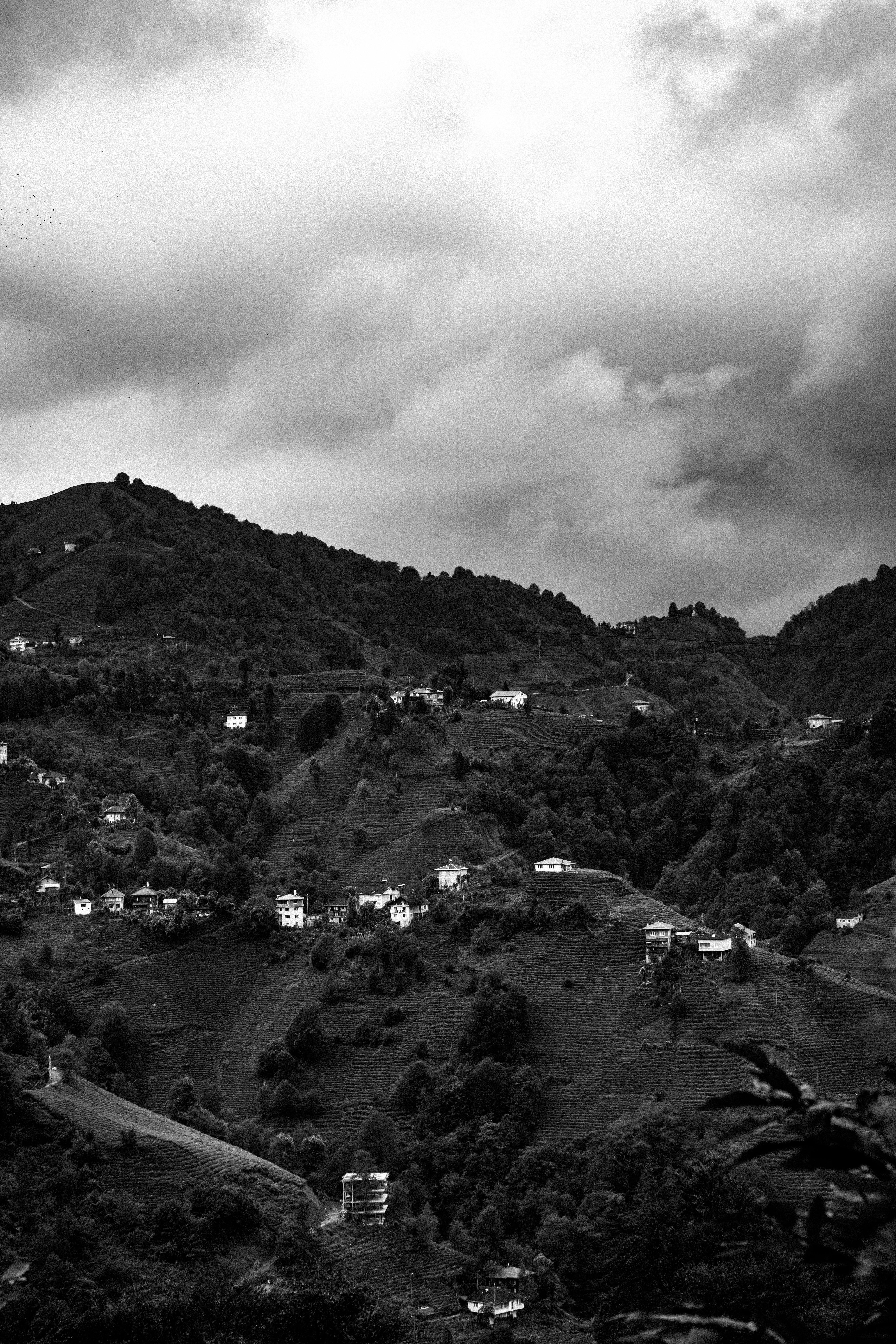Black and white image of a mountainous landscape under a dramatic cloudy sky.