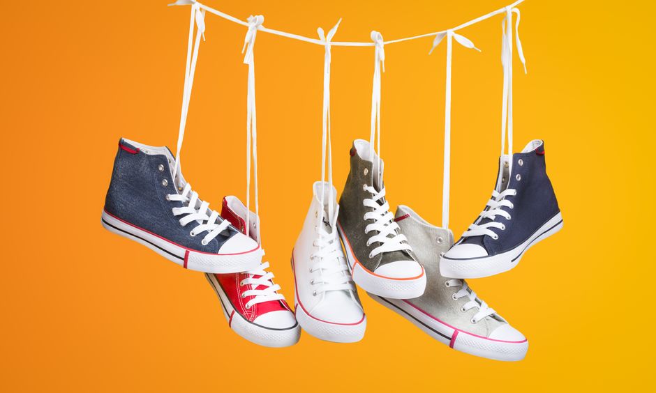 AI Background Remover Tools for Product Photography Without Photoshop Stylish sneakers in various colors hanging with laces on a vivid orange backdrop. Ideal for fashion themes.