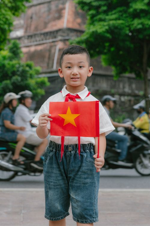 Free Young boy proudly holds Vietnamese flag on busy city street, symbolizing patriotism. Stock Photo
