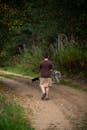 A boy walking down a dirt road with a dog