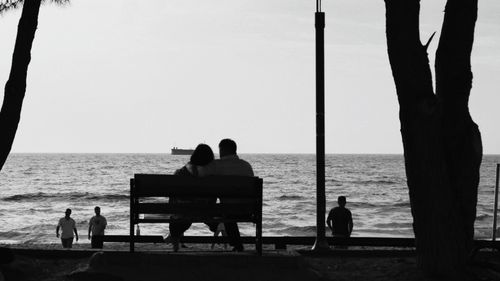 Free A romantic moment captured with silhouettes of a couple by the sea at sunset. Stock Photo
