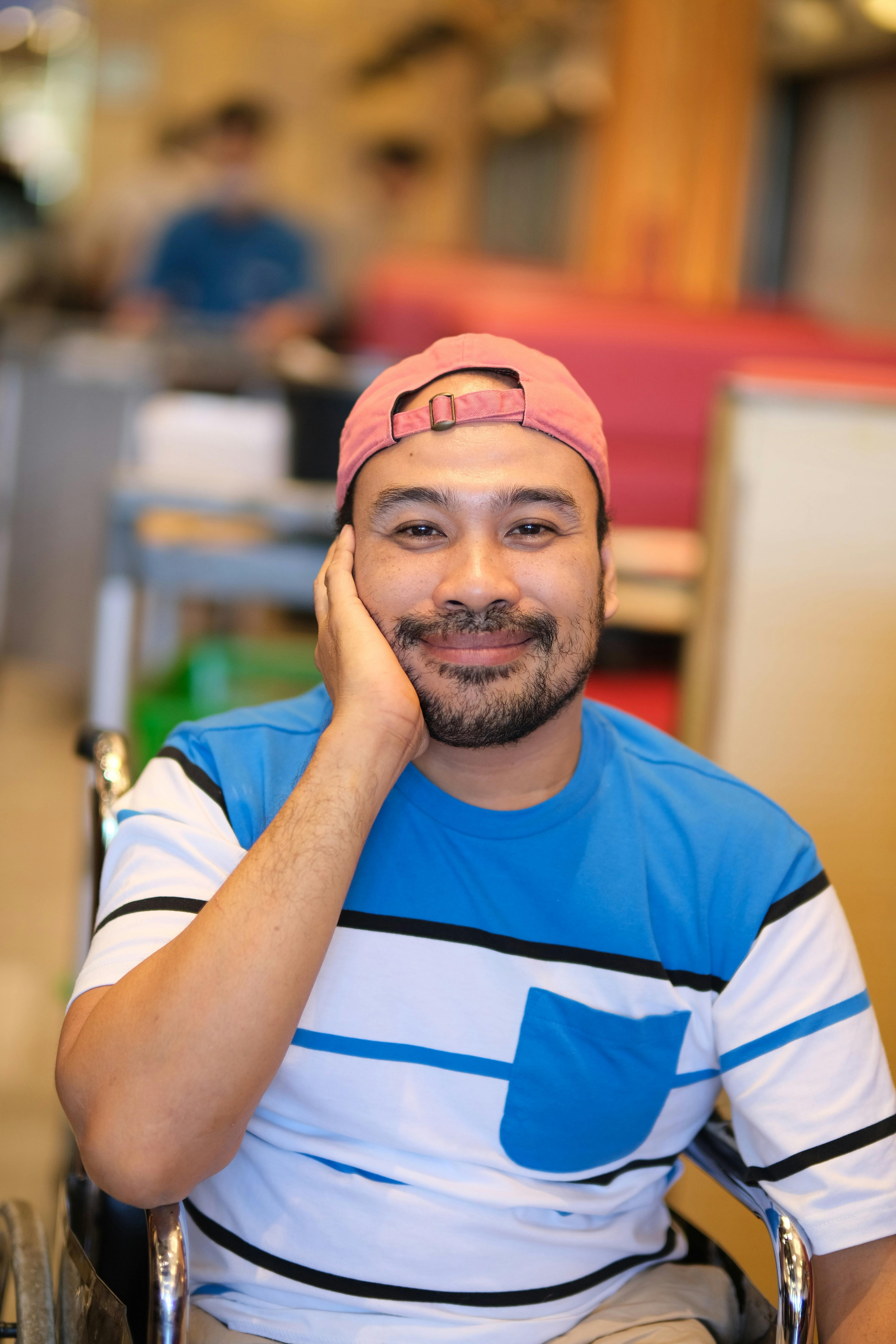 a smiling man in a wheelchair with a hat on