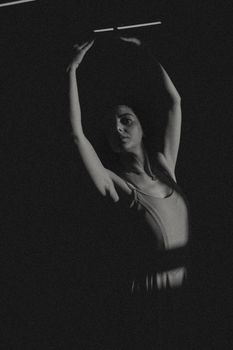 A graceful ballerina strikes a delicate pose in a moody black and white setting, showcasing her art and elegance.