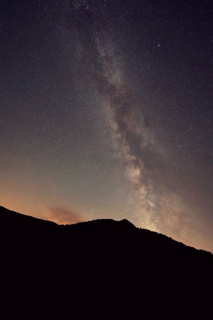 Capture of the Milky Way galaxy above a silhouetted mountain at twilight.