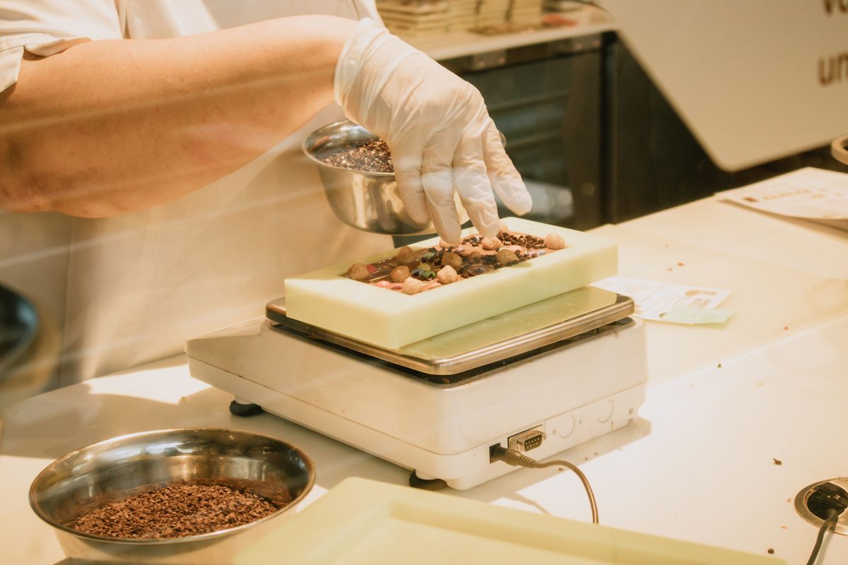 Mãos de confeiteiro com luvas pesando trufas artesanais de chocolate