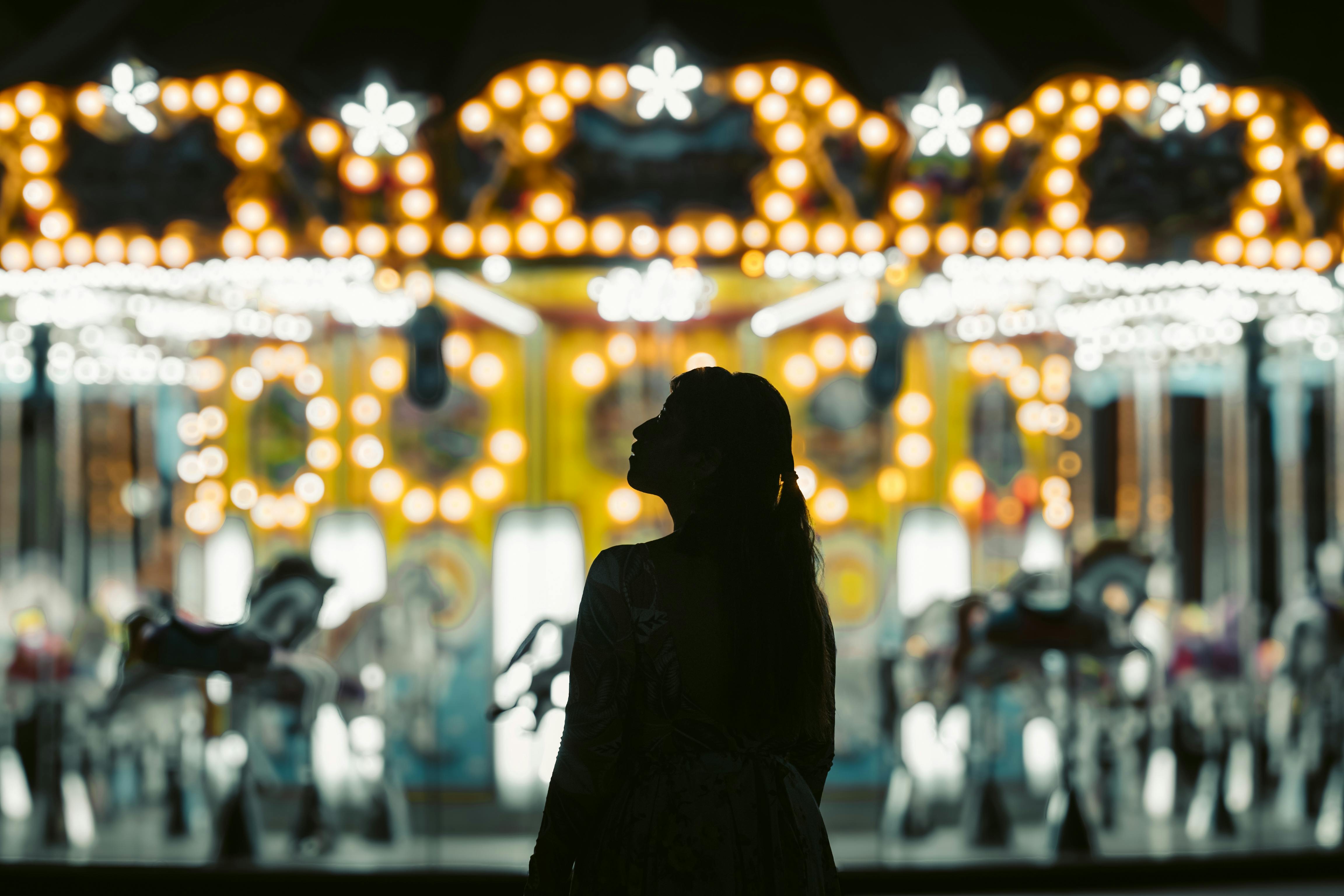 a woman standing in front of a carousel at night