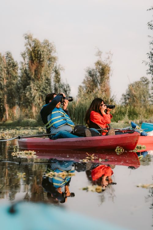 Free Two adults kayaking on a calm lake with cameras, capturing nature's beauty. Perfect leisure activity. Stock Photo