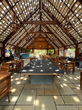 Spacious wooden interior with rustic design, ideal for dining or events, featuring natural sunlight.