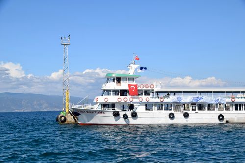 Free A ferry sailing in the ocean displaying a Turkish flag, near a coastal pier. Stock Photo