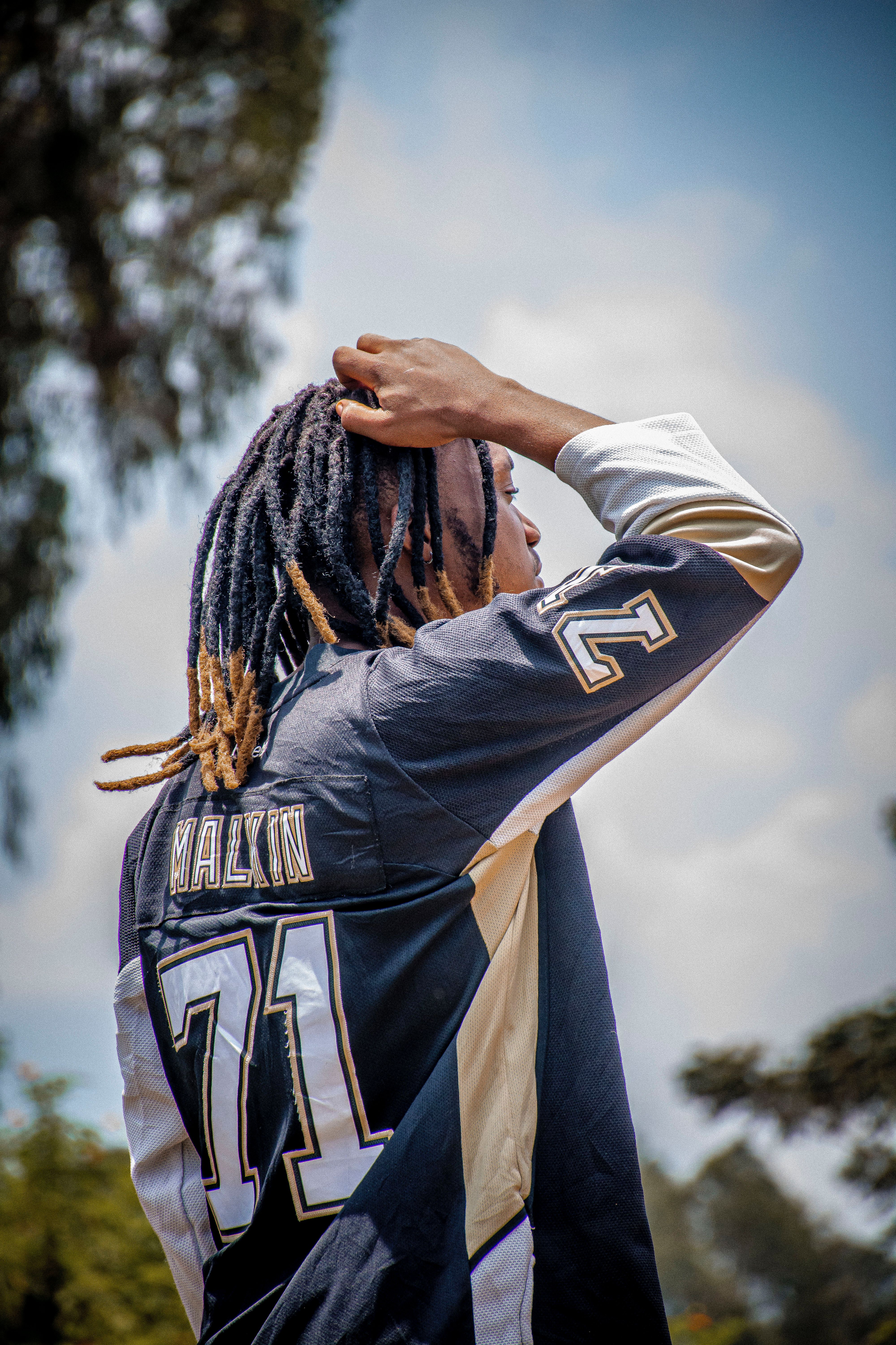 A young adult wearing a sports jersey outdoors, enjoying a sunny day.