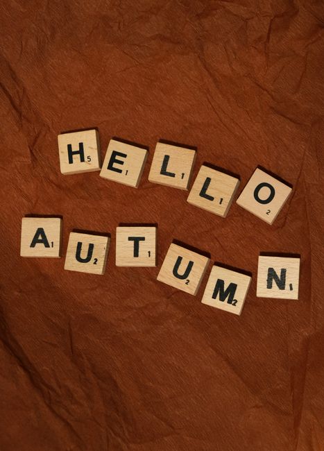 Wooden letters on brown paper spelling 'Hello Autumn' welcoming fall season.
