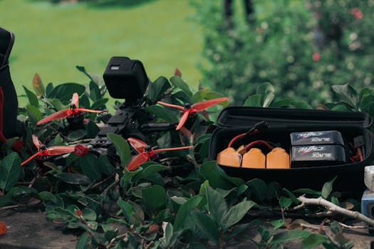 Aerial drone with equipment laid out among garden foliage on a sunny day.