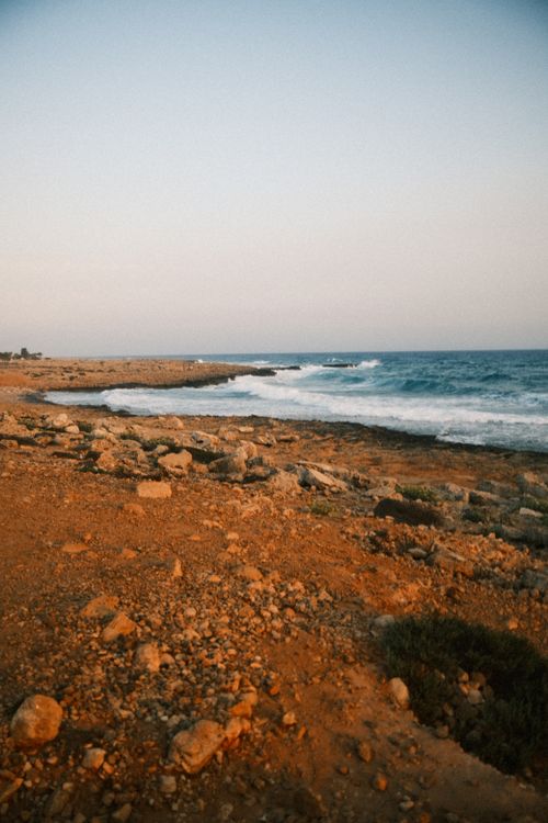 Free Explore the tranquil rocky coastline of Cyprus with waves crashing at sunset. Stock Photo