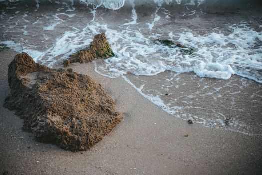 A rock on the beach with waves crashing into it