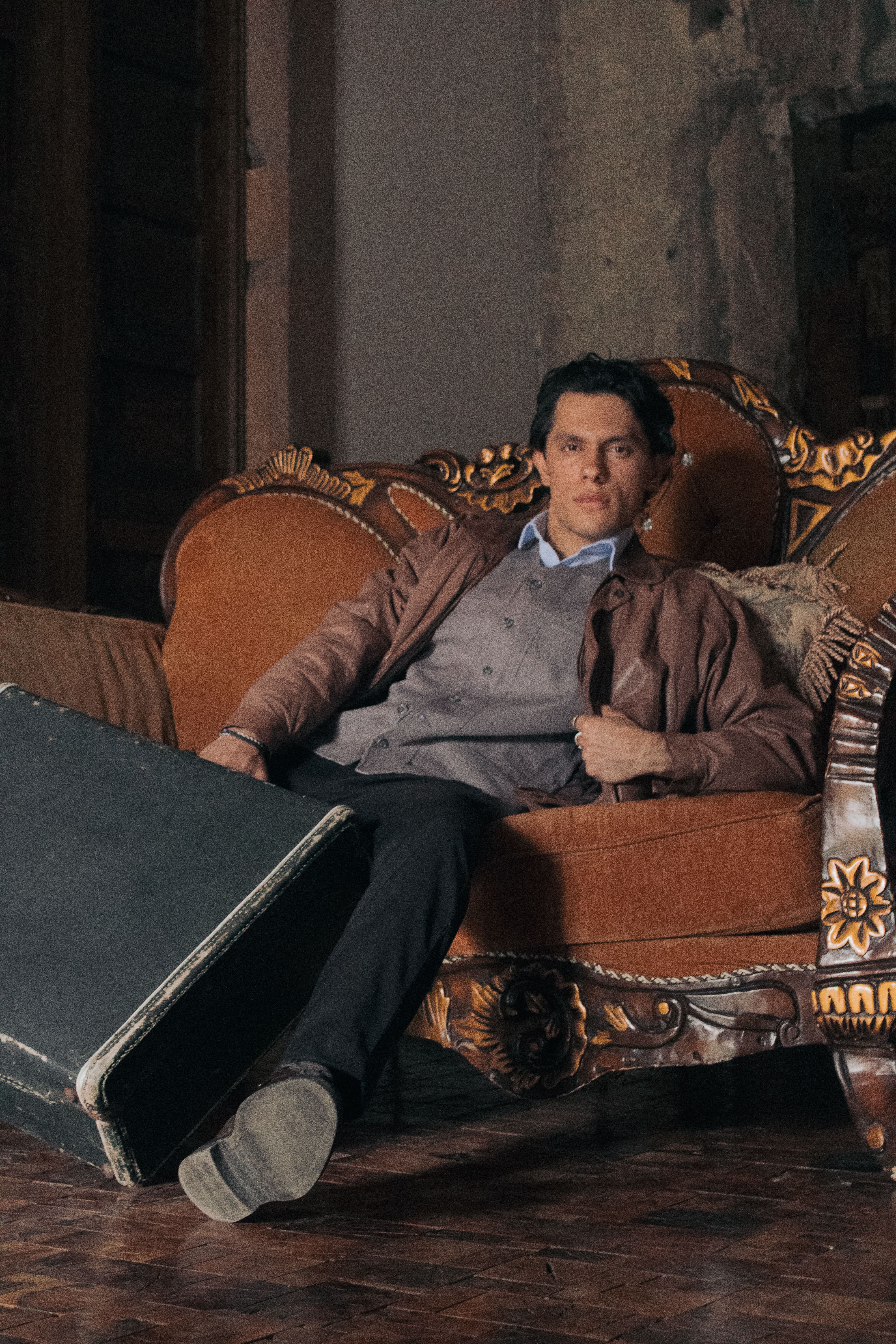 Young man in vintage setting, relaxing with a guitar case, exuding a warm and cozy ambiance.