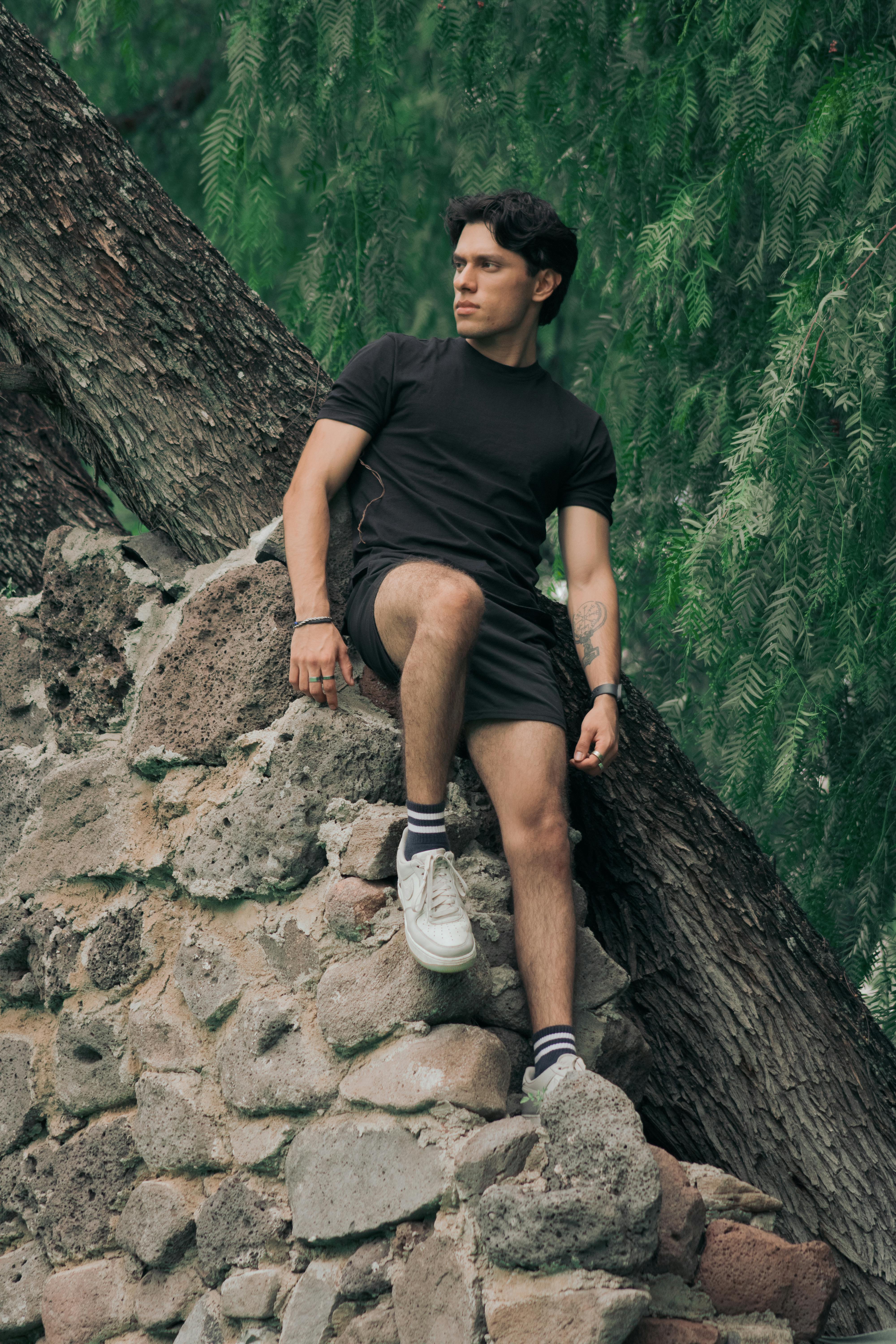 A young man relaxing on a rock wall surrounded by trees in León, Mexico.