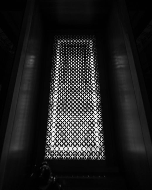 Detailed view of a metal grate with geometric designs in England. Black and white photo.