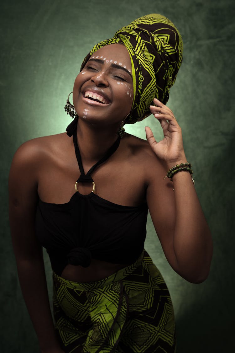 Photo Of Smiling Woman In African Headscarf And Skirt And Black Halter Top Laughing With Her Eyes Closed