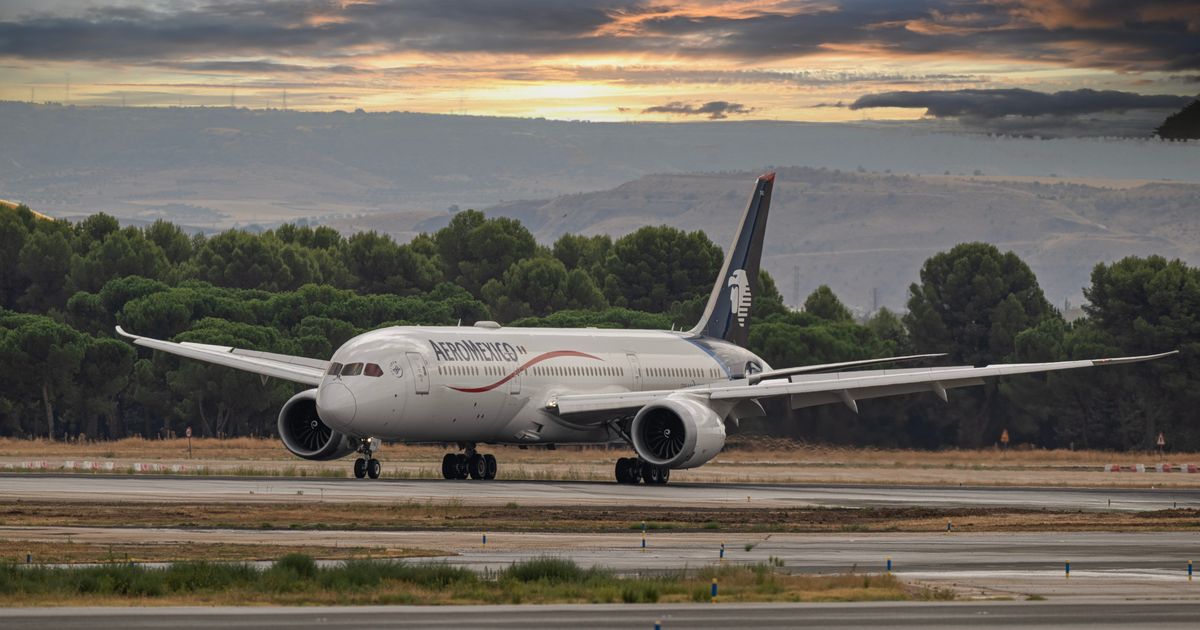 A large passenger jet on an airport runway at sunset.