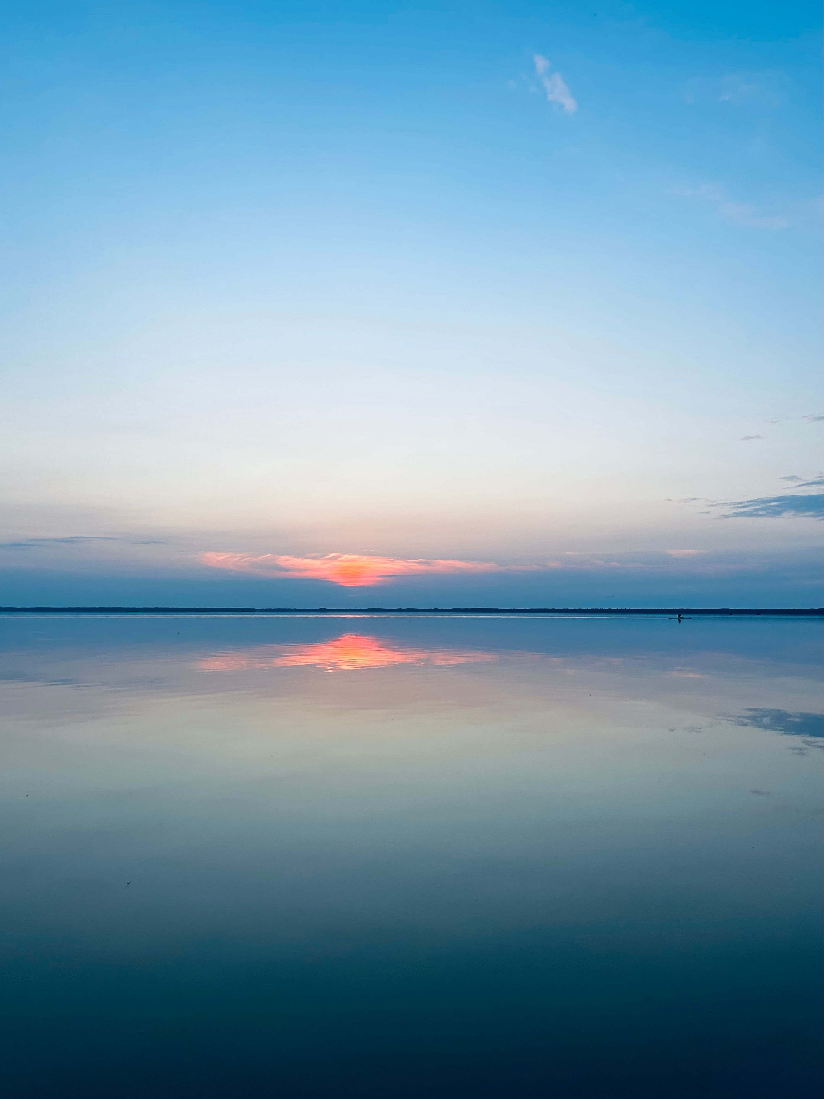 A sunset over a calm lake with a reflection · Free Stock Photo