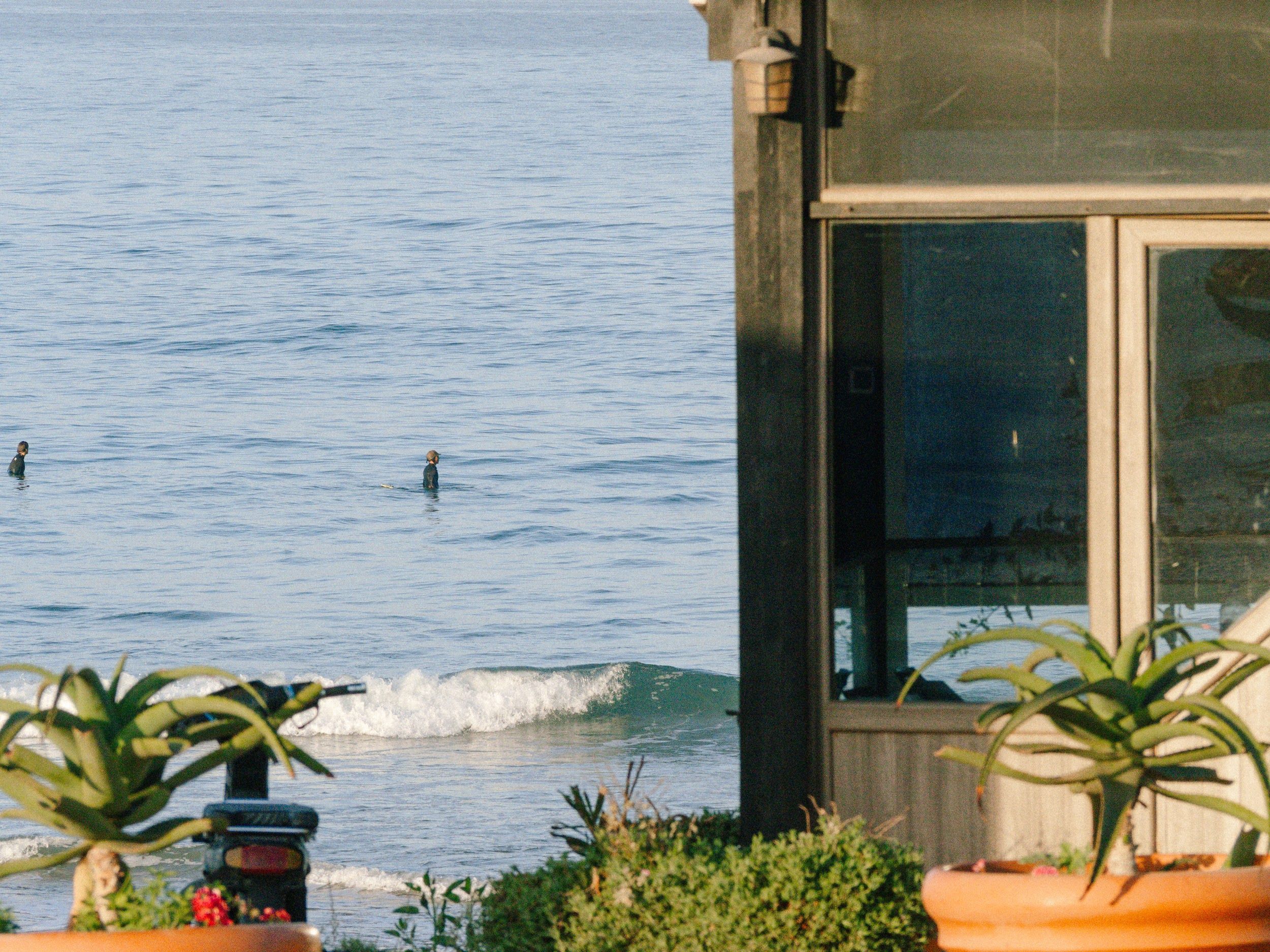 Relaxing ocean view from a porch in Taghazout, Morocco, with surfers in the distance.