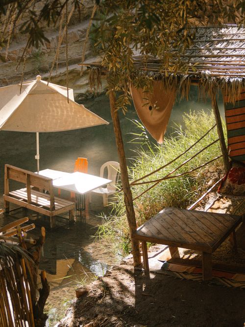 Free Charming outdoor seating area by the river in Taghazout, Morocco with chairs and umbrellas. Stock Photo