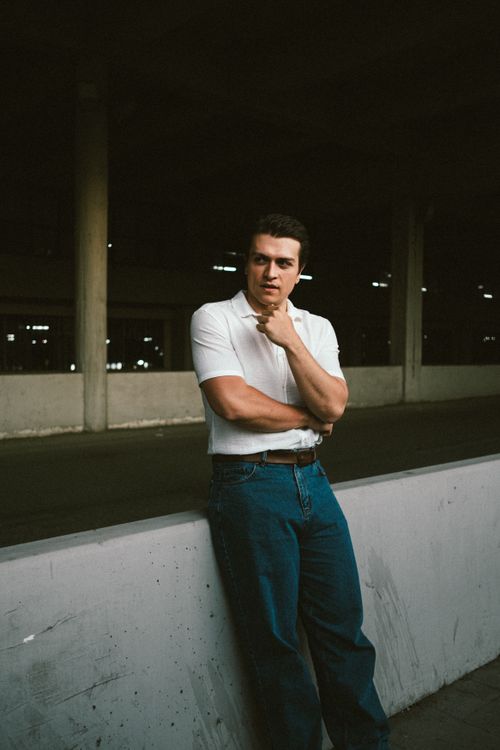 A man in jeans leaning against a concrete wall · Free Stock Photo