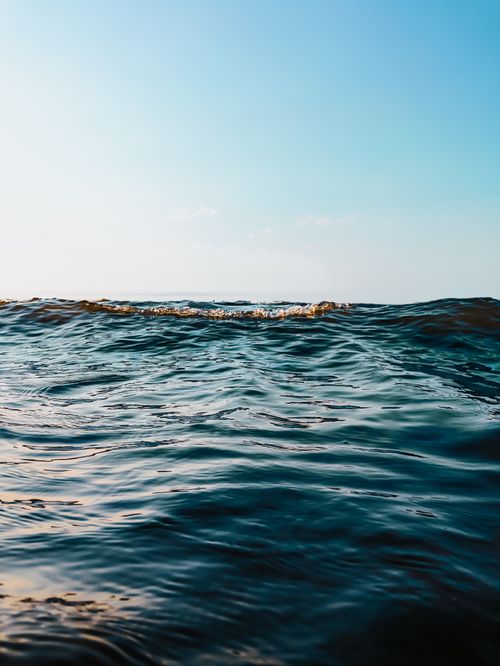 Free Peaceful ocean waves under a clear sky at sunset in Fereydunkenar, Iran. Stock Photo