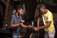 Two young mechanics working on a car engine outdoors in Mozambique.