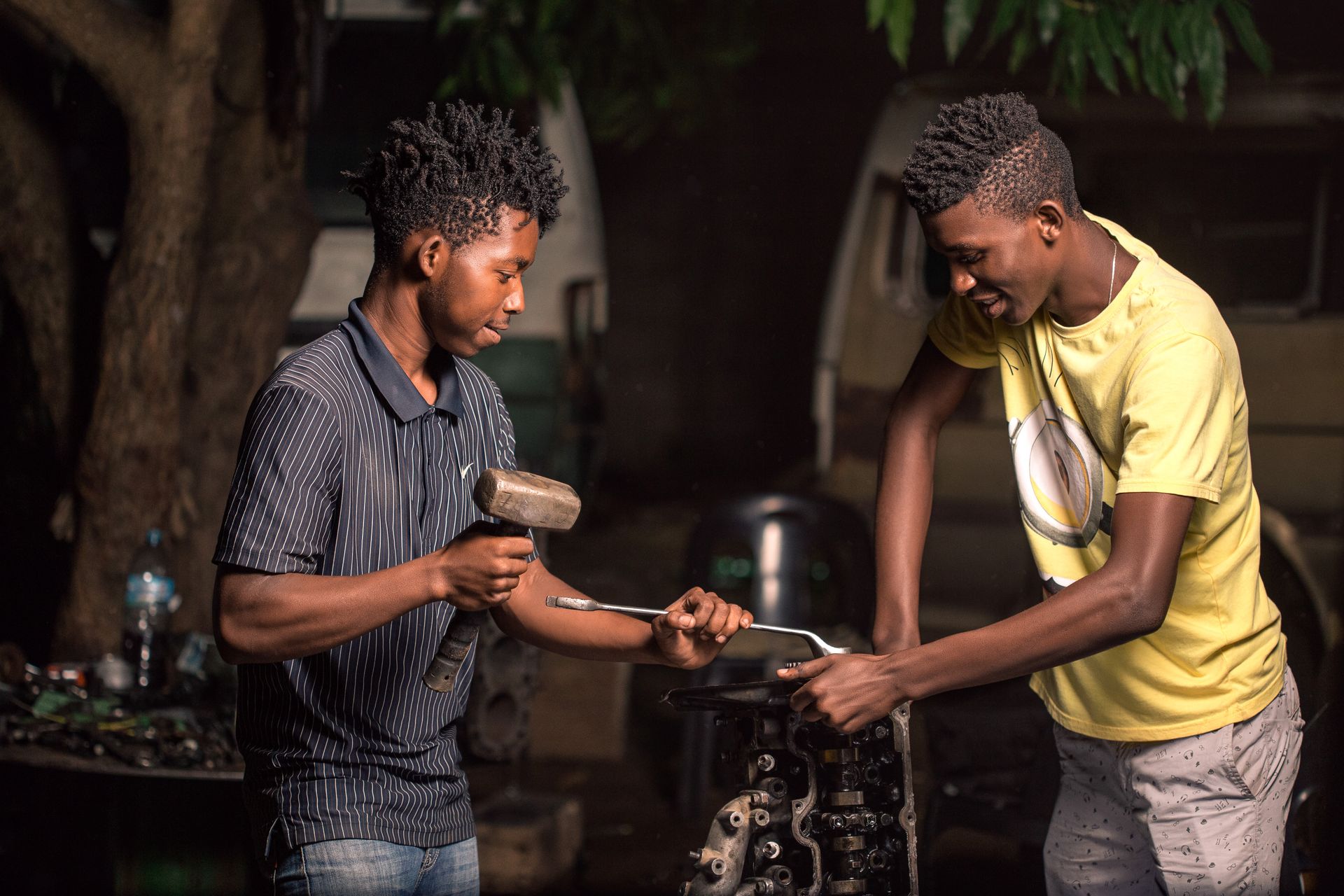 Men Repairing Engine with Wrench and Hammer