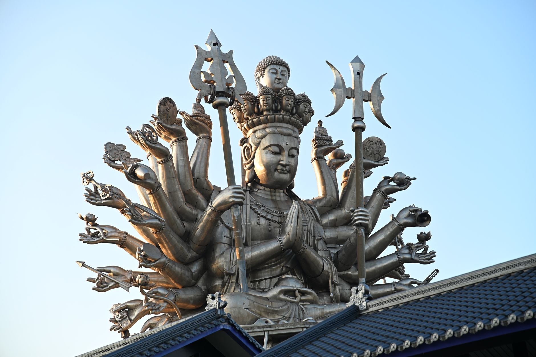 Majestic bronze Thousand-Armed Guanyin statue under clear sky in New Taipei City, Taiwan.