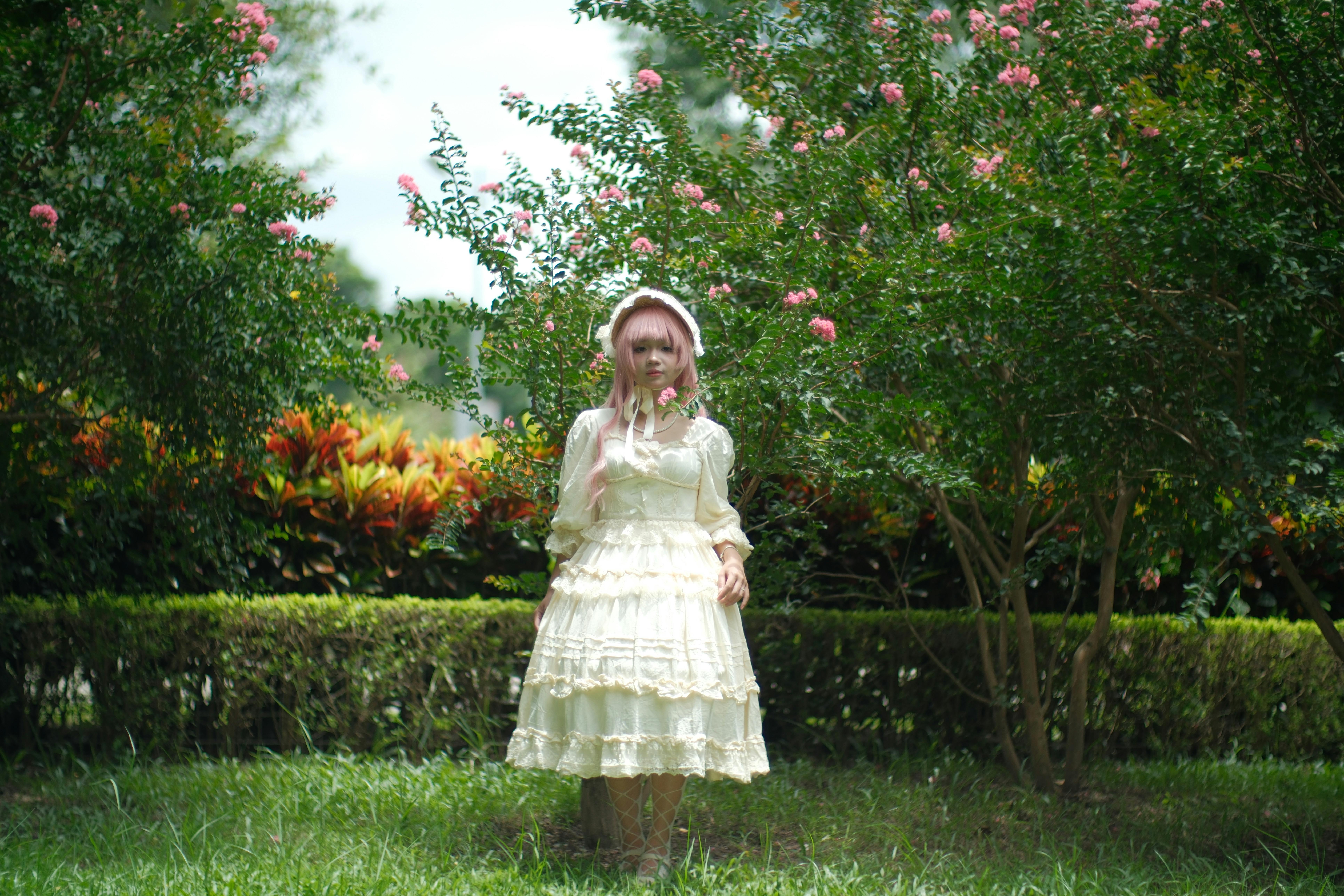 a little girl in a white dress standing in the grass