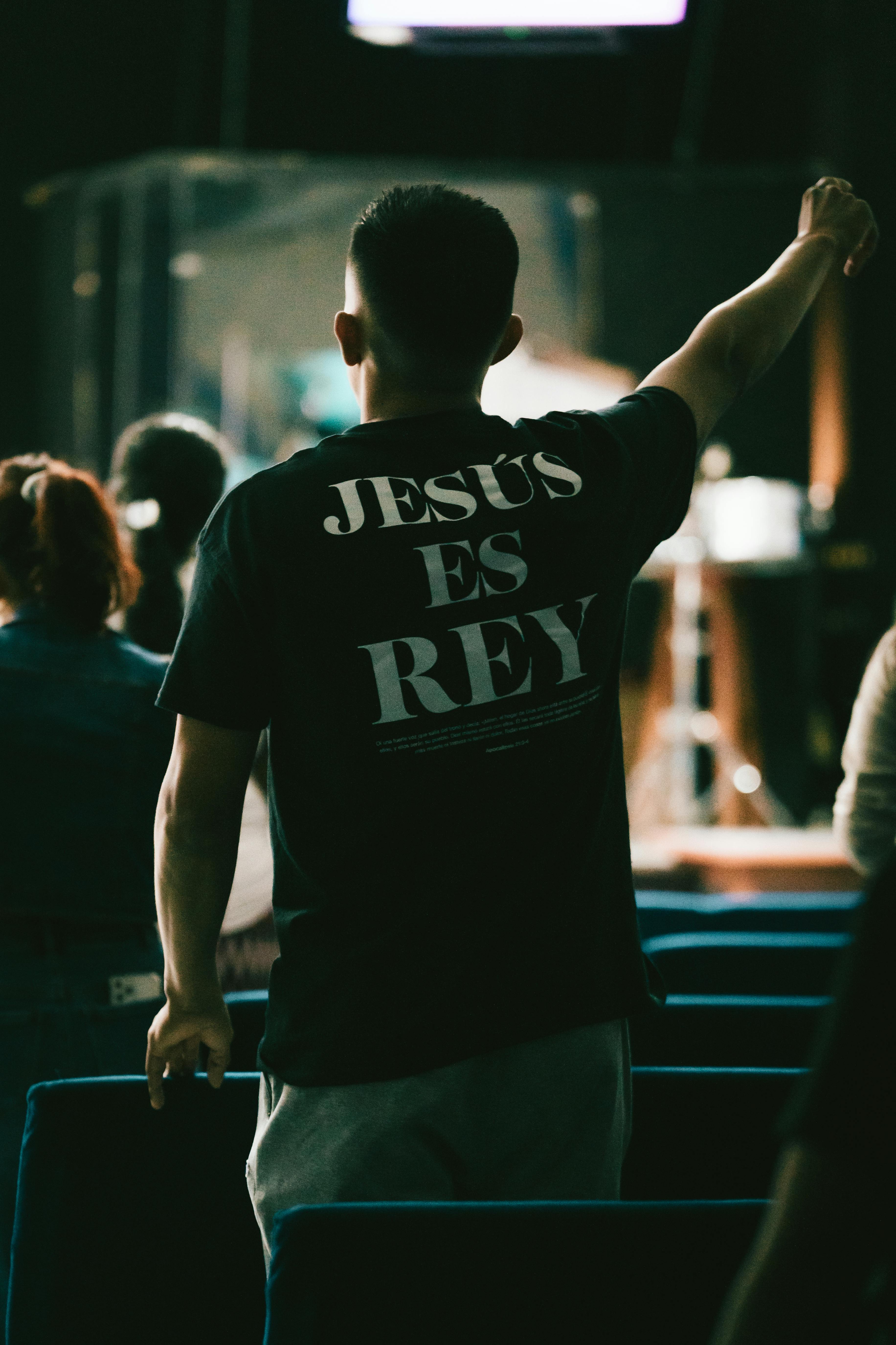 a man wearing a shirt that says jesus is rey