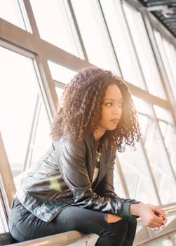 一位卷发时尚女性身处光线充足的现代室内，肖像自然