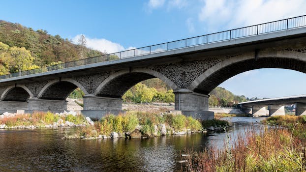 Idyllic stone bridge spanning Edersee river in lush summer landscape, perfect for travel and architecture enthusiasts.