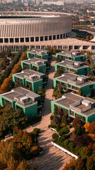 A top view of modern architectural buildings surrounded by gardens under clear skies.