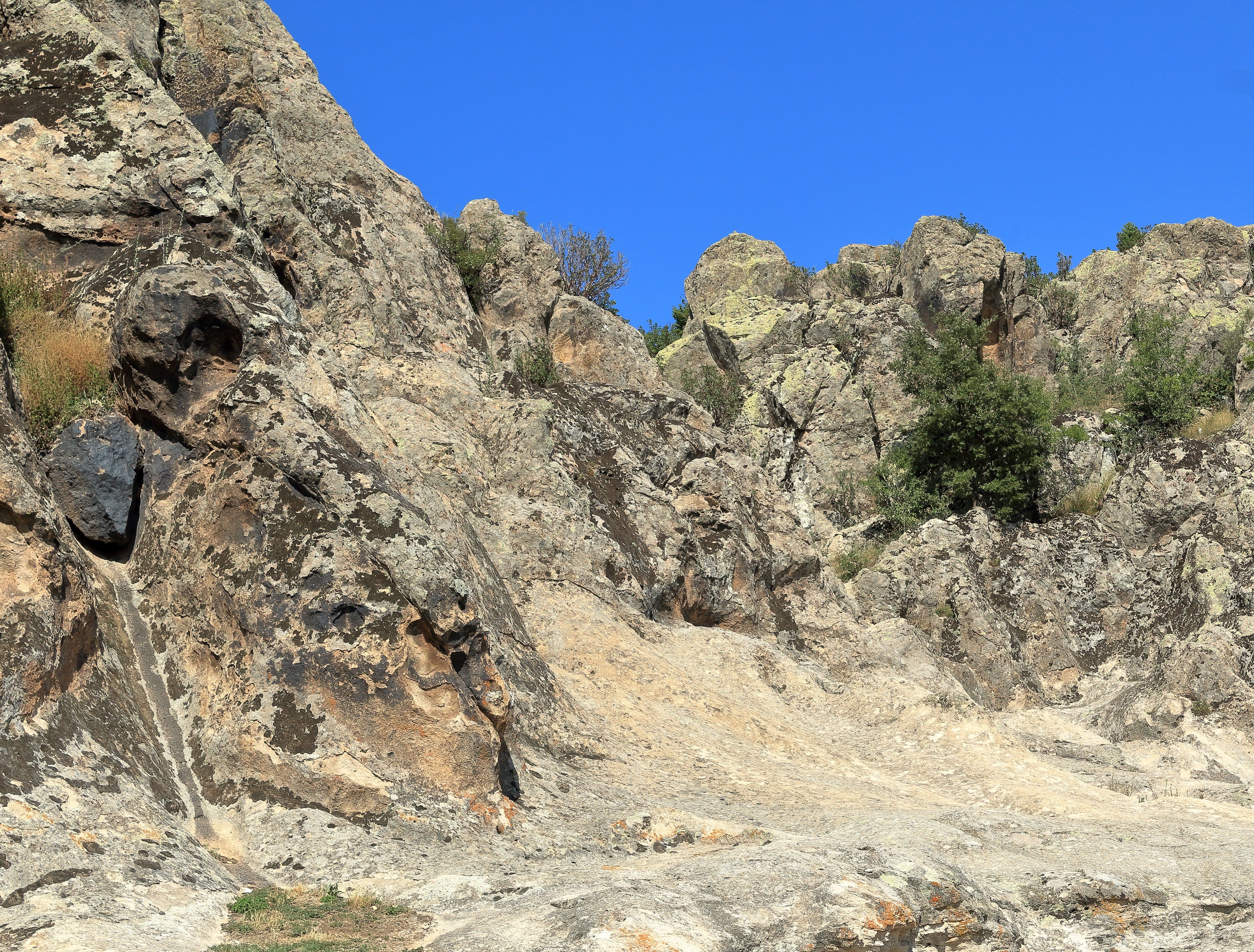 A rocky mountain with a blue sky and some trees · Free Stock Photo