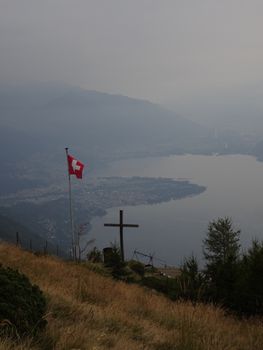 Majestic view of Lake Maggiore from Locarno, Switzerland with a cross and Swiss flag.