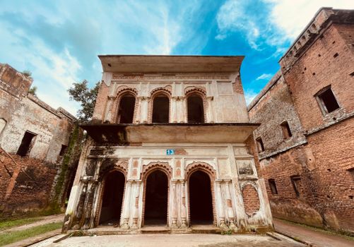 A historic abandoned building with intricate arched windows and blue sky background.