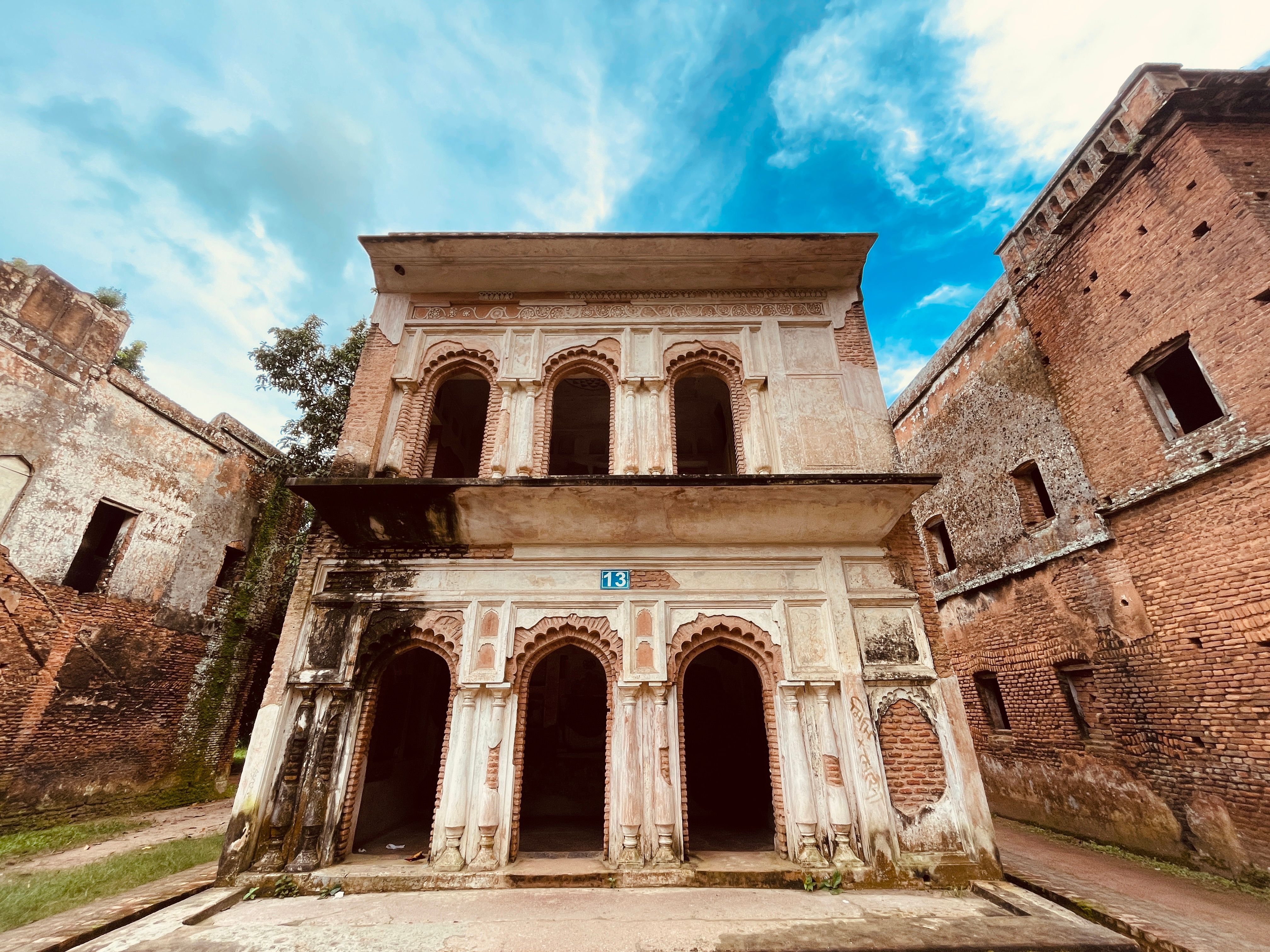 Ancient two-story brick building with arched designs under a clear blue sky.