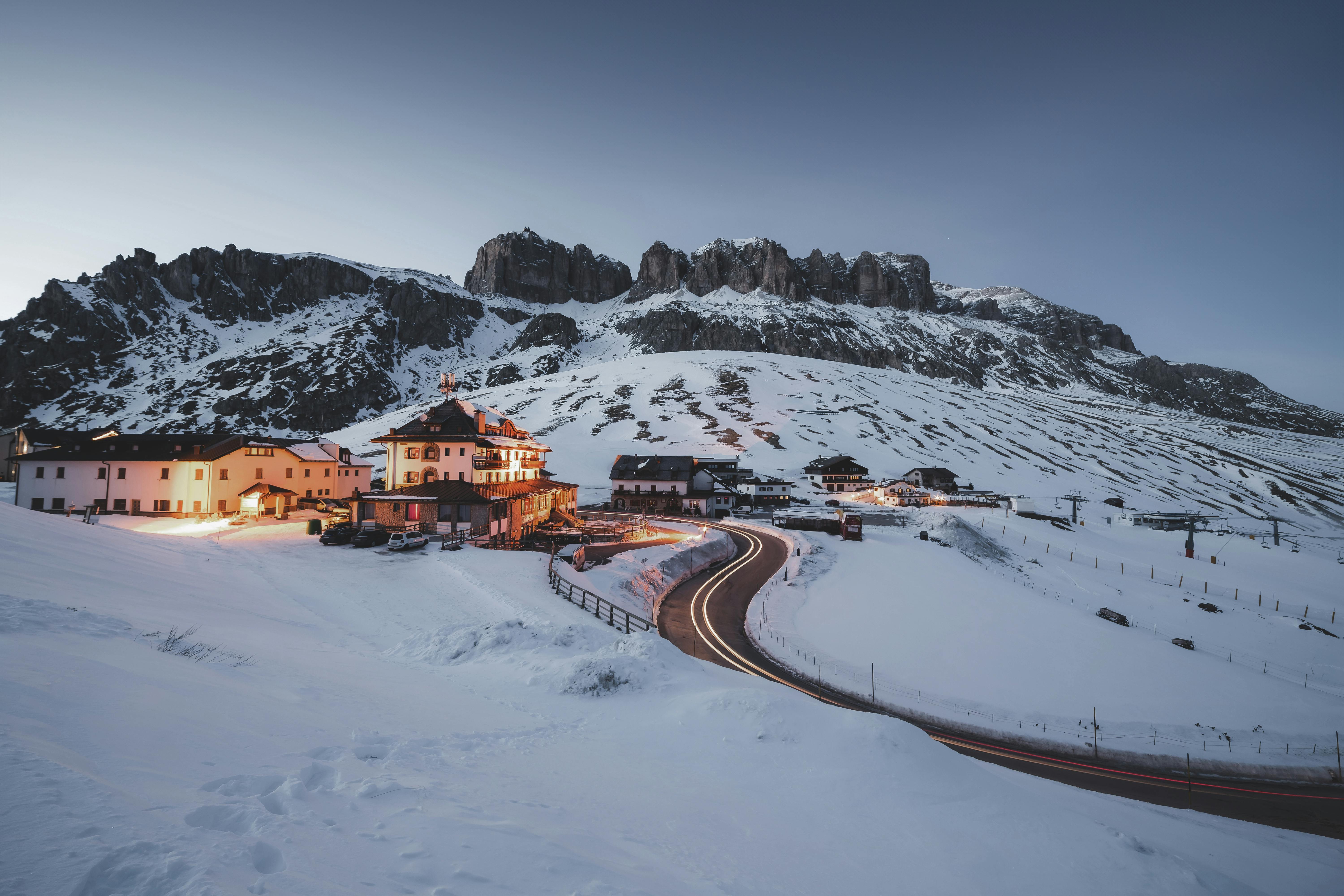 A picturesque mountain resort nestled in snowy peaks at twilight, illuminated warmly.