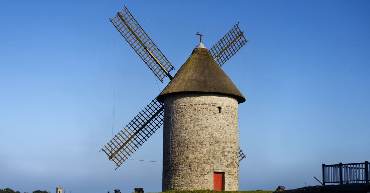 A traditional windmill tower in Skerries, Ireland, under a clear blue sky.