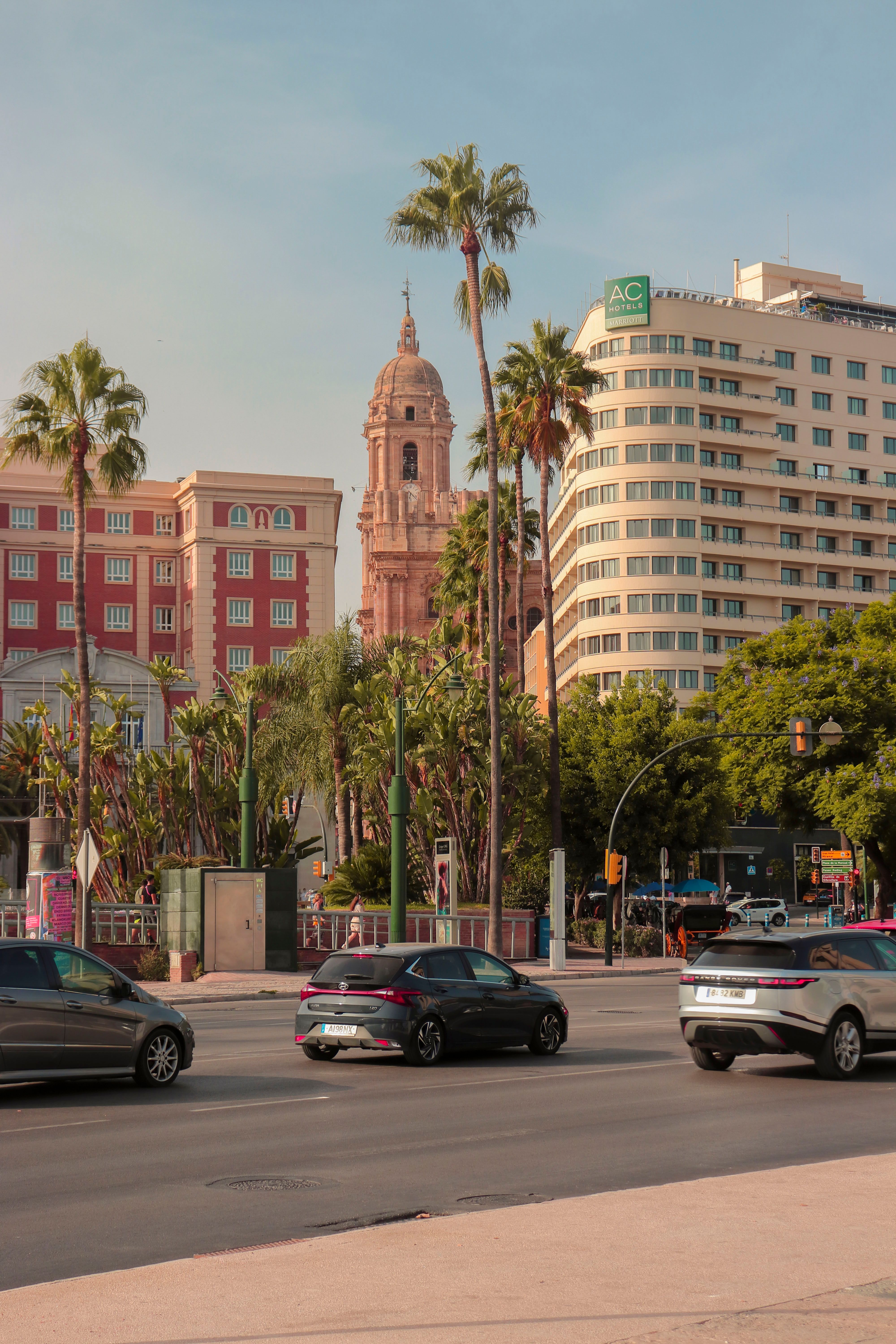View of a modern city with historic architecture, trees, and busy street traffic.