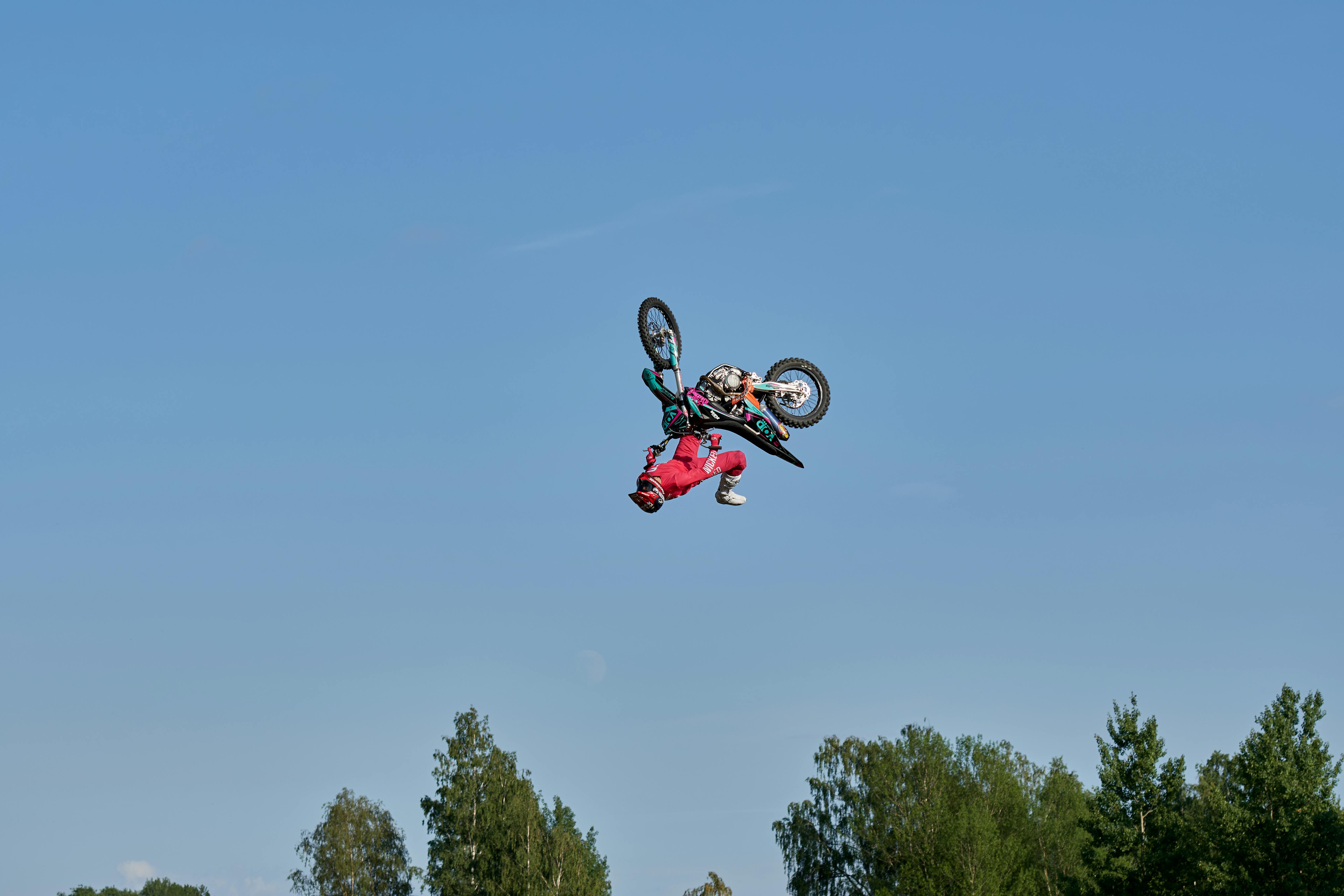 Daring motocross stunt against a clear blue sky, showcasing extreme sports excellence.