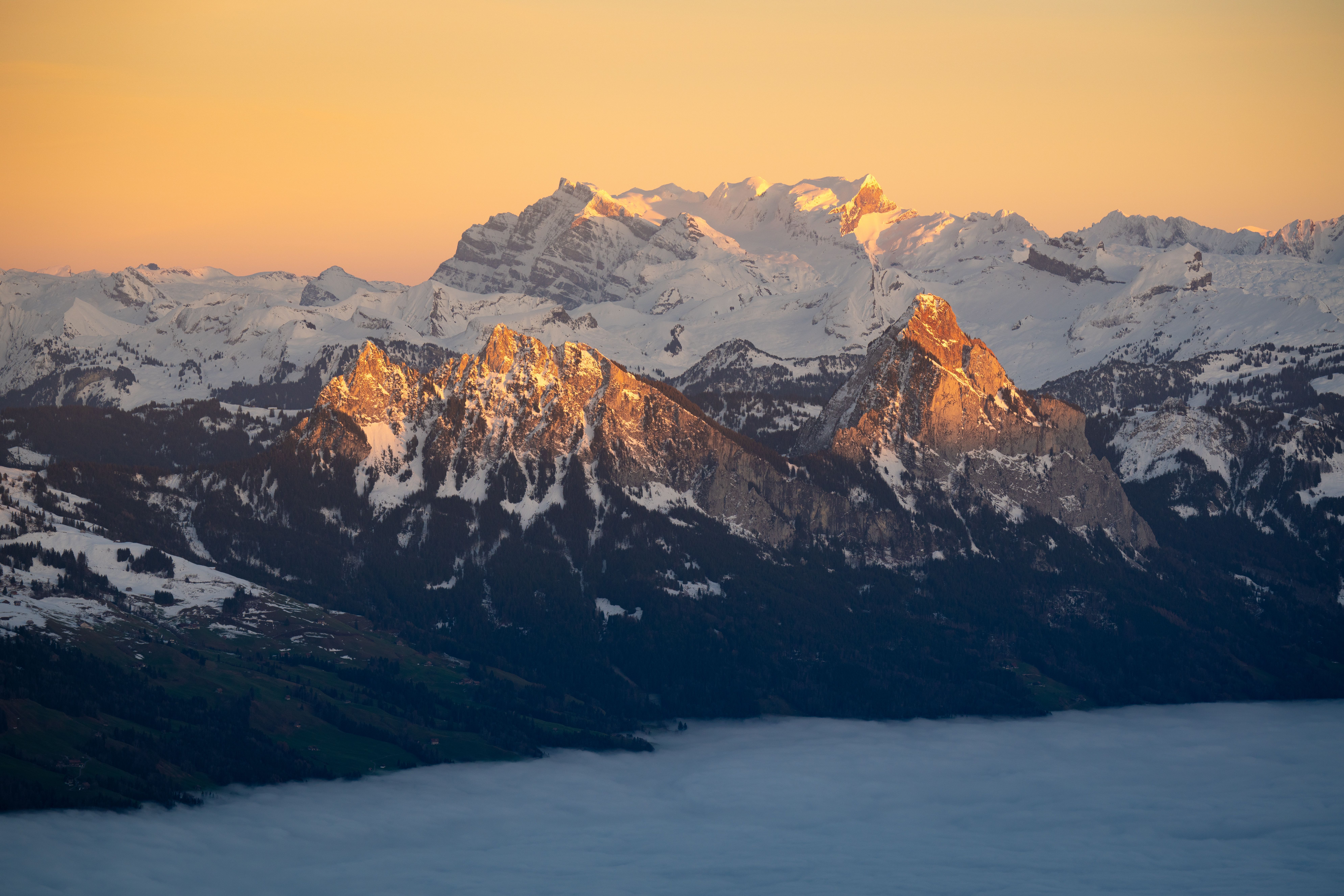 Breathtaking view of snow-capped mountains illuminated by sunset glow, capturing winter's majestic beauty.