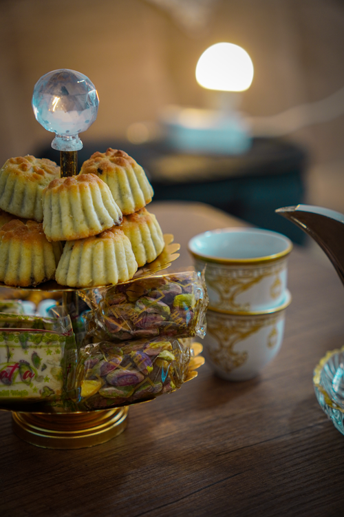 Free A beautifully arranged platter of Middle Eastern sweets and stacked tea cups in a warm indoor setting. Stock Photo