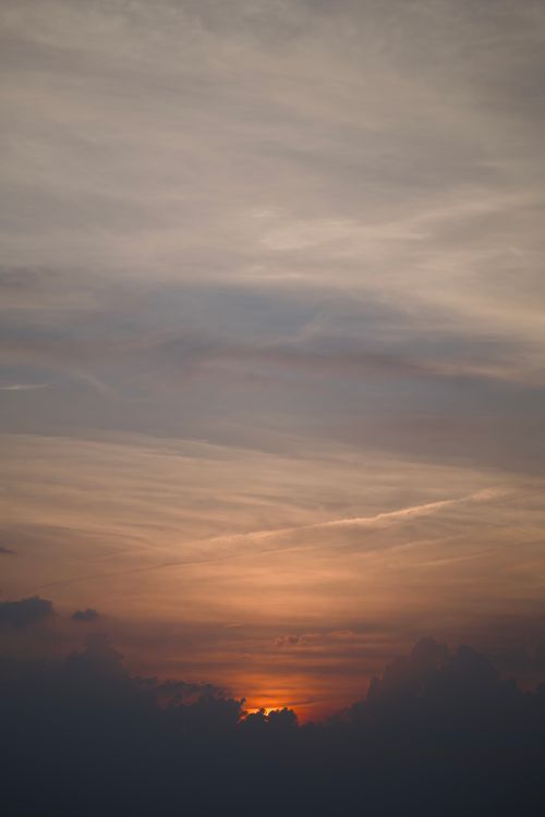 Free A calming sunset scene with an orange sky and clouds, perfect for backgrounds. Stock Photo
